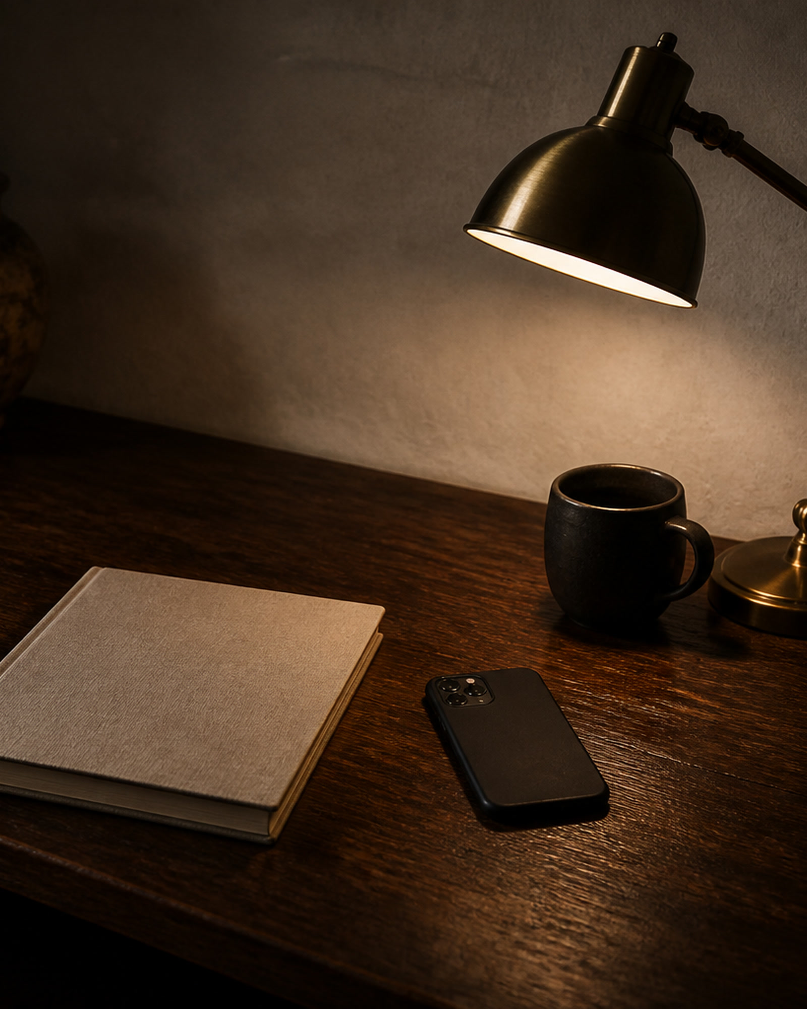 Desk lamp over a notebook, a phone, and a mug.
