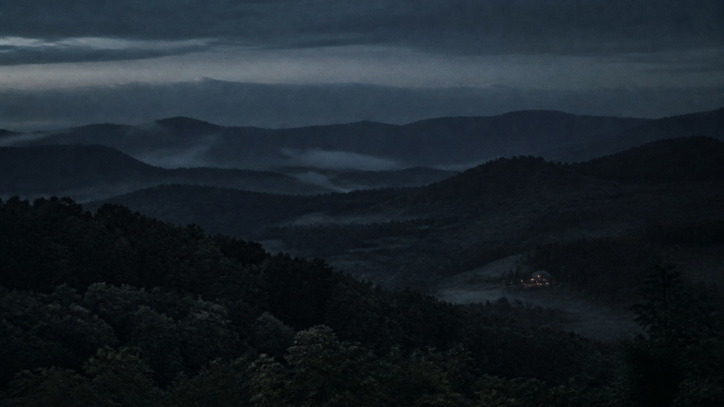 Blue hour over the ridges west of Asheville, one porch light in the valley.